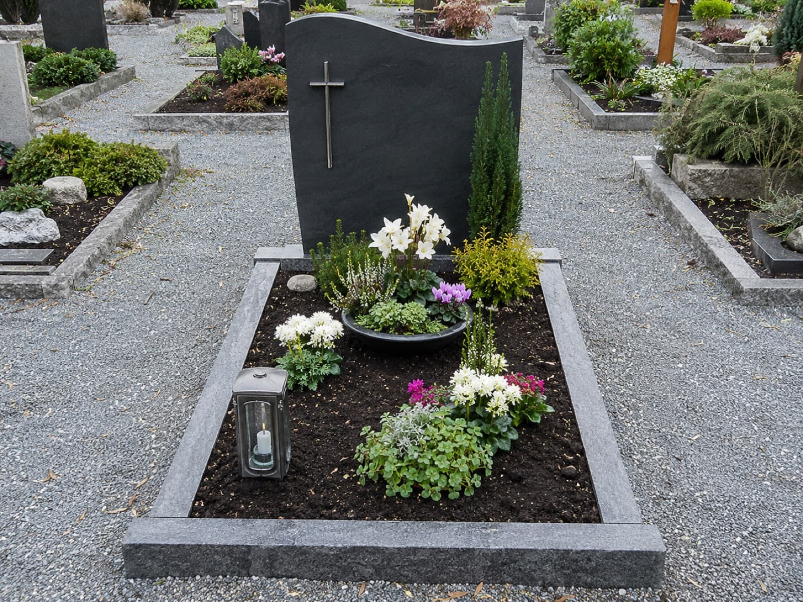 Naturnah bepflanztes, frisch gepflegtes Grab mit Bodendeckern und Blüten